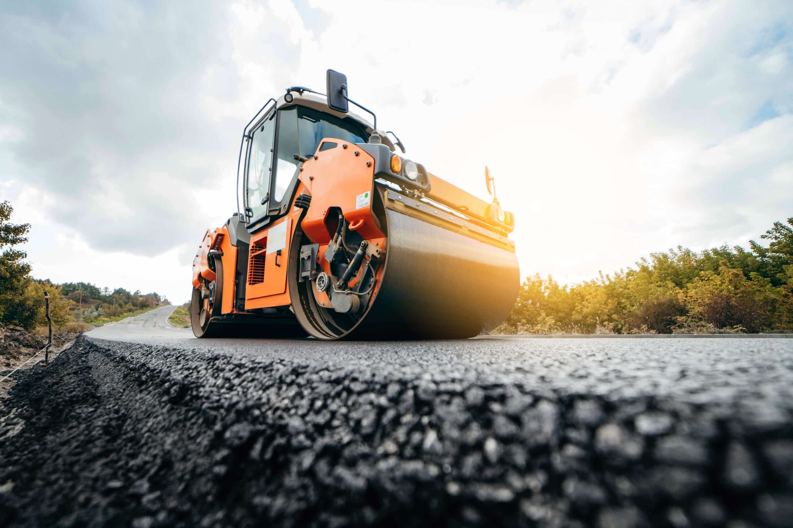 A vibratory roller compacting hot mix asphalt on a paving project